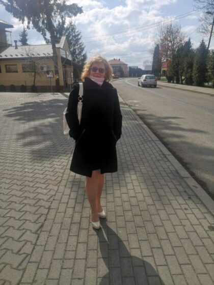młoda kobieta w płaszczu stoi na chodniku
